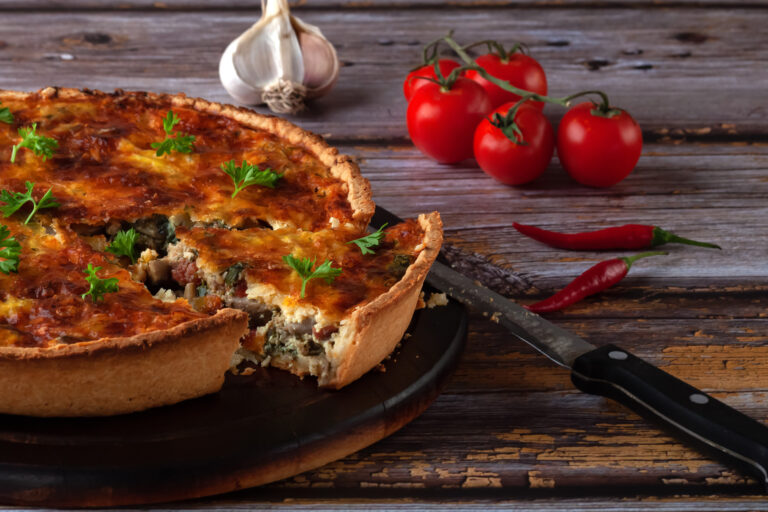 Traditional french quiche pie with chicken and mushroom on a wooden background